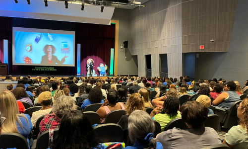   Hundreds of pre-K staff listen to a keynote speaker in Palisades High's auditorium